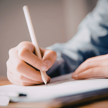 Hand writing with a pencil on a piece of paper.